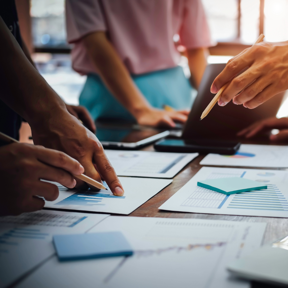 Closeup photo of people pointing at graphs on a table
