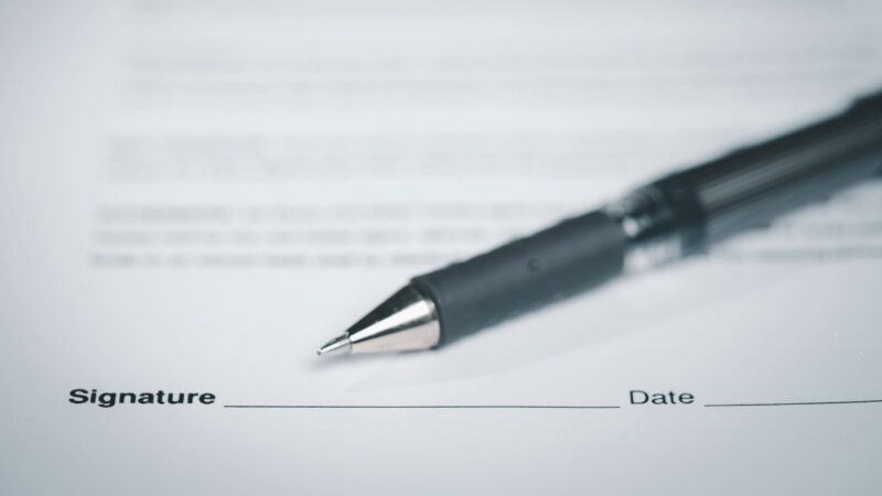 A pen on a sheet of paper with lines for signature and date.